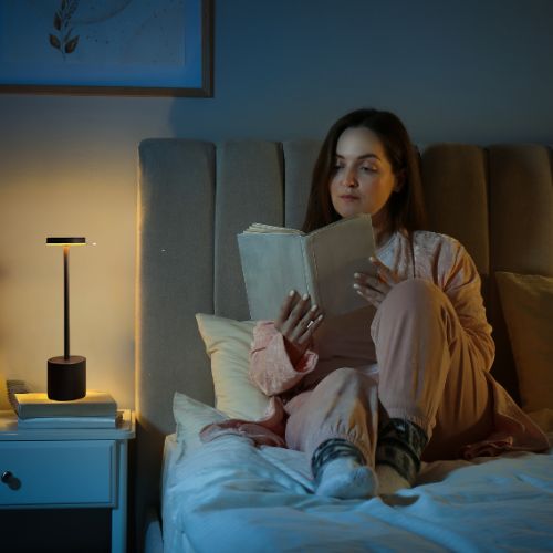 femme lecture dans son lit avec lampe de chevet aura