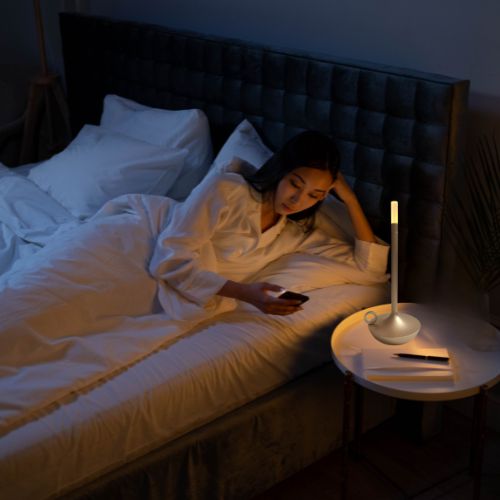 femme lit regarde telephone lampe de chevet